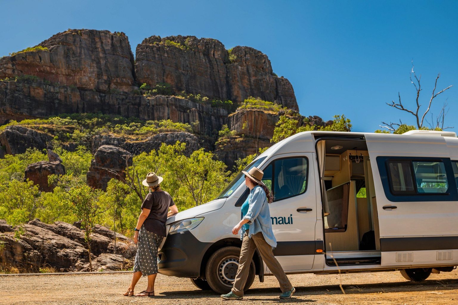 Couple unloading a campervan below towering sandstone cliffs, Kakadu National Park, the Northern Territory
