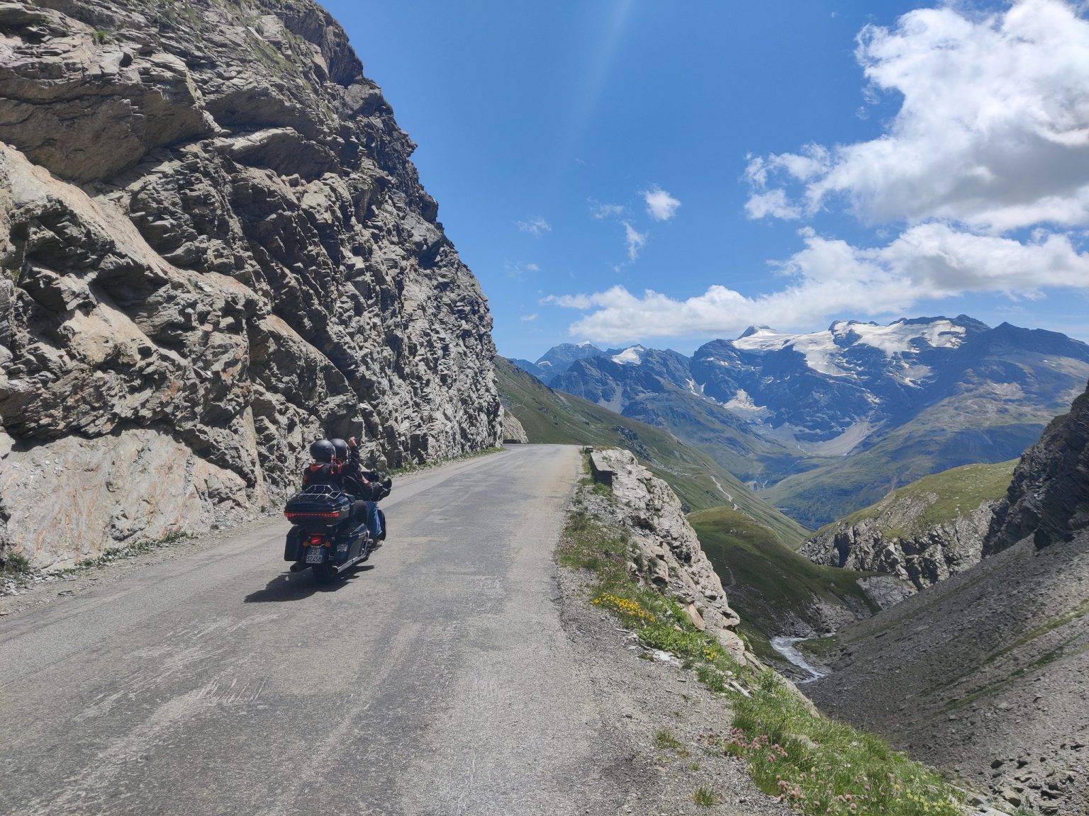 Motorcyclist on a narrow cliffside road in the Italian Alps