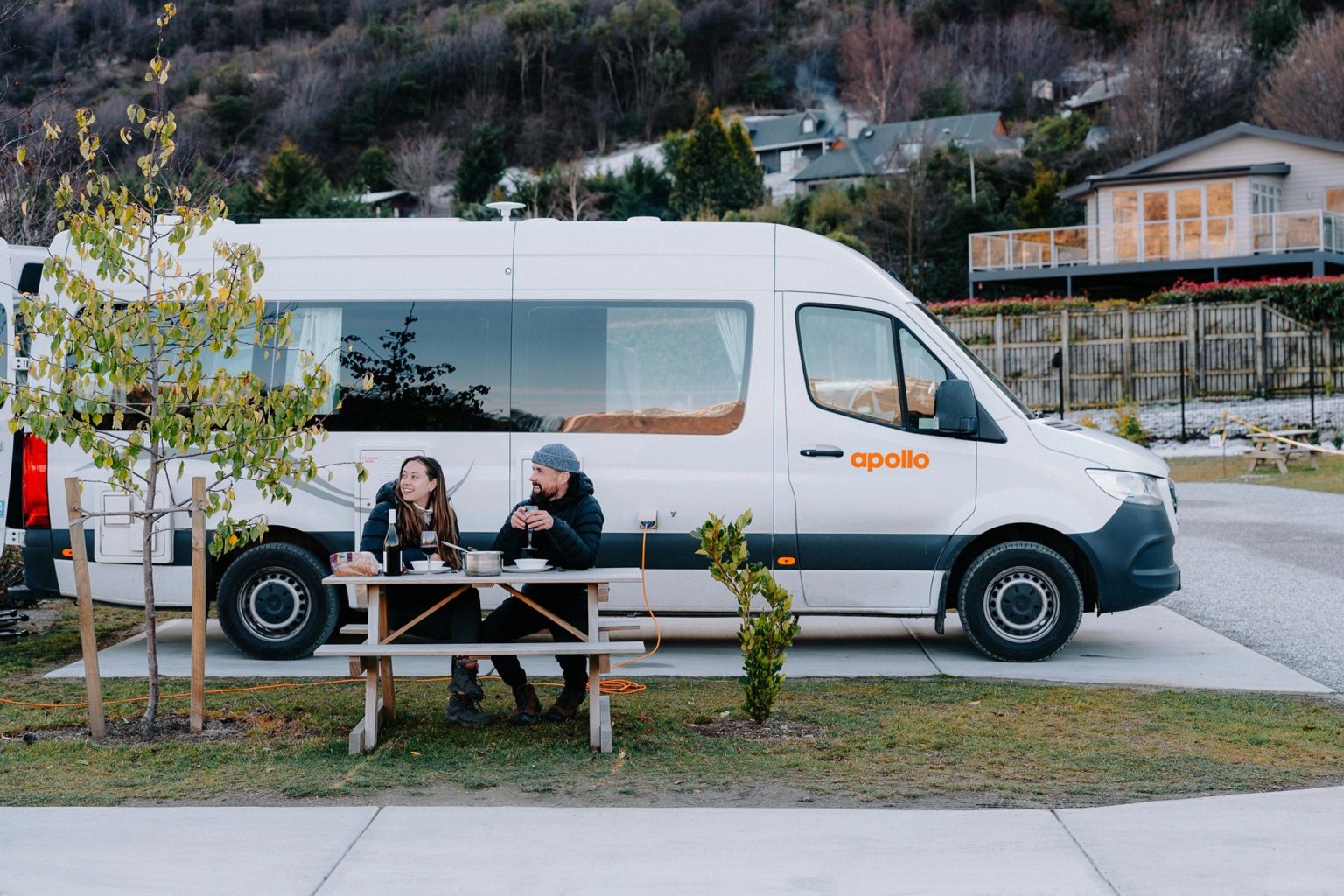 Couple at a picnic table beside a campervan at a campsite, Queenstown, New Zealand's South Island