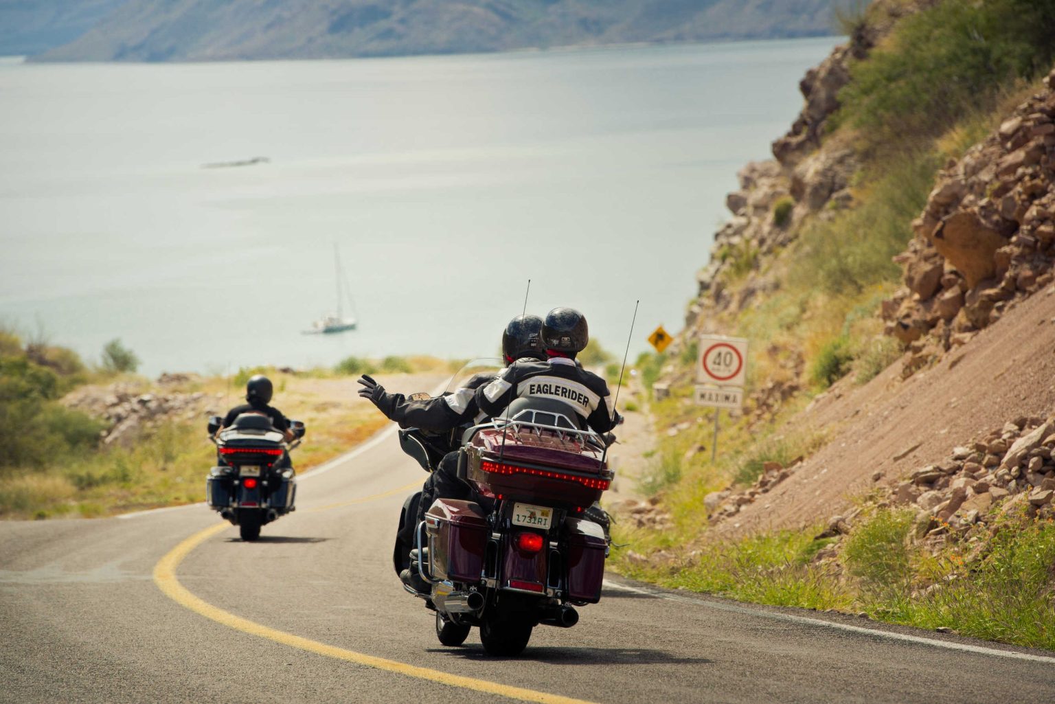 Riders on touring motorcycles on a coastal bend above a bay in Baja