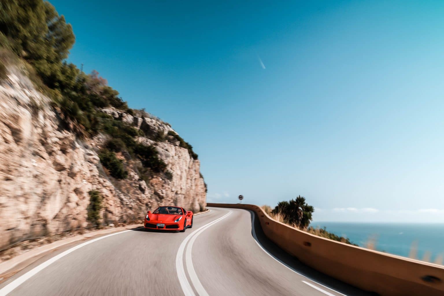 Red Ferrari on a coastal road above the Mediterranean