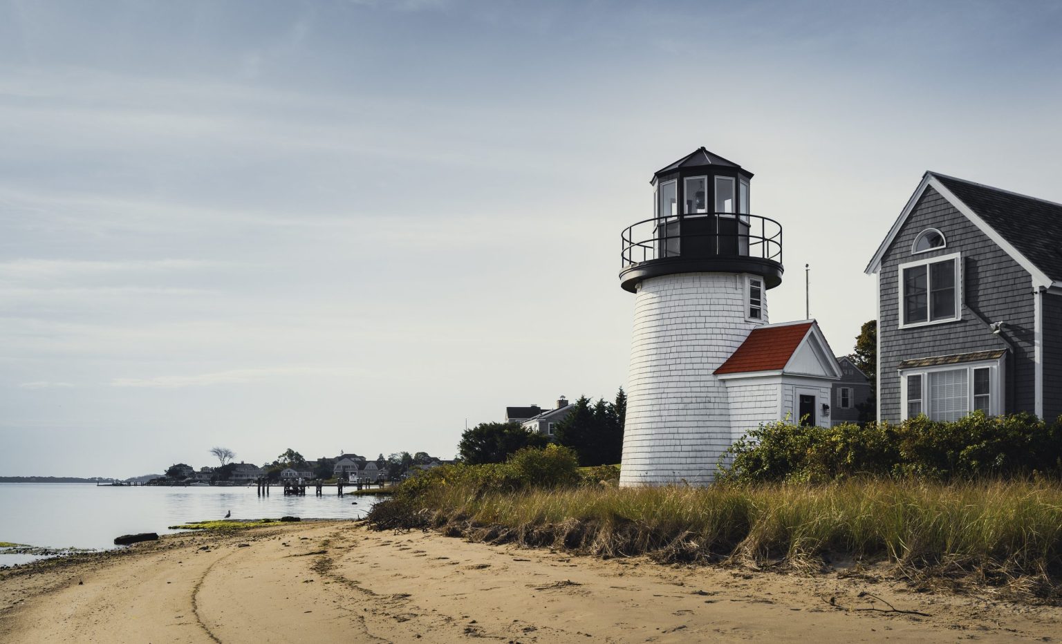 Lighthouse and shingled cottage on a Cape Cod beach, Massachusetts