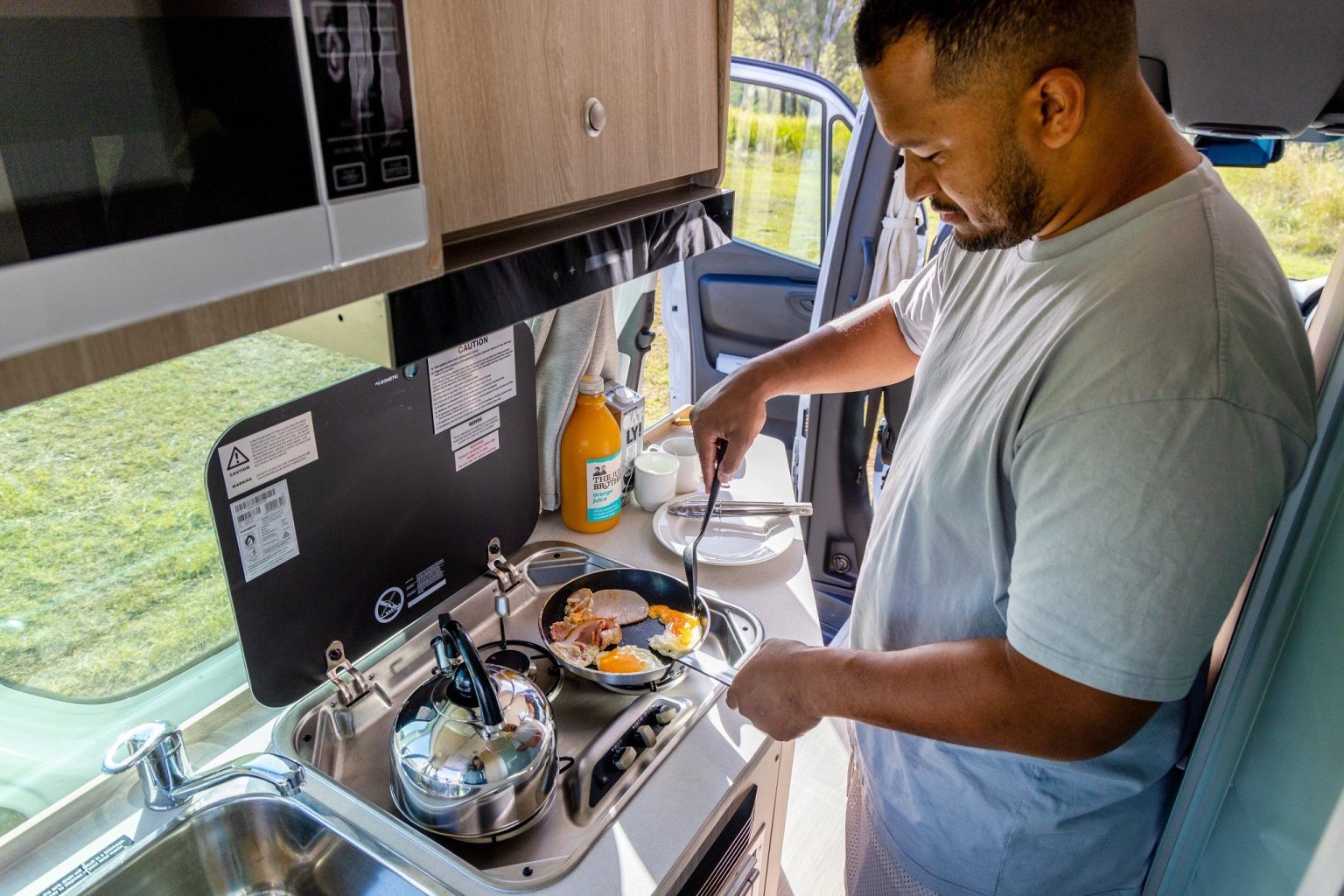 Man cooking at the campervan hob, South East Queensland