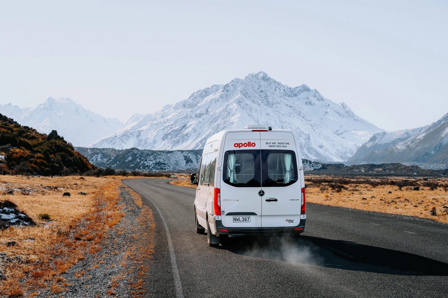 Campervan on a road heading away from a snowy mountain, Mount Cook, New Zealand's South Island