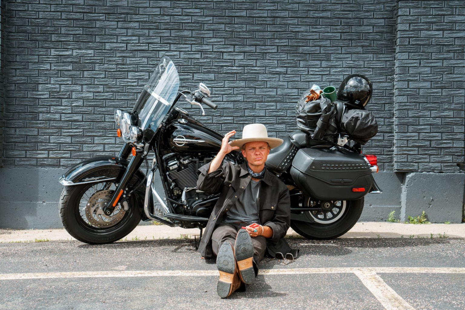 Rider in a cowboy hat sitting beside a Harley-Davidson touring motorcycle