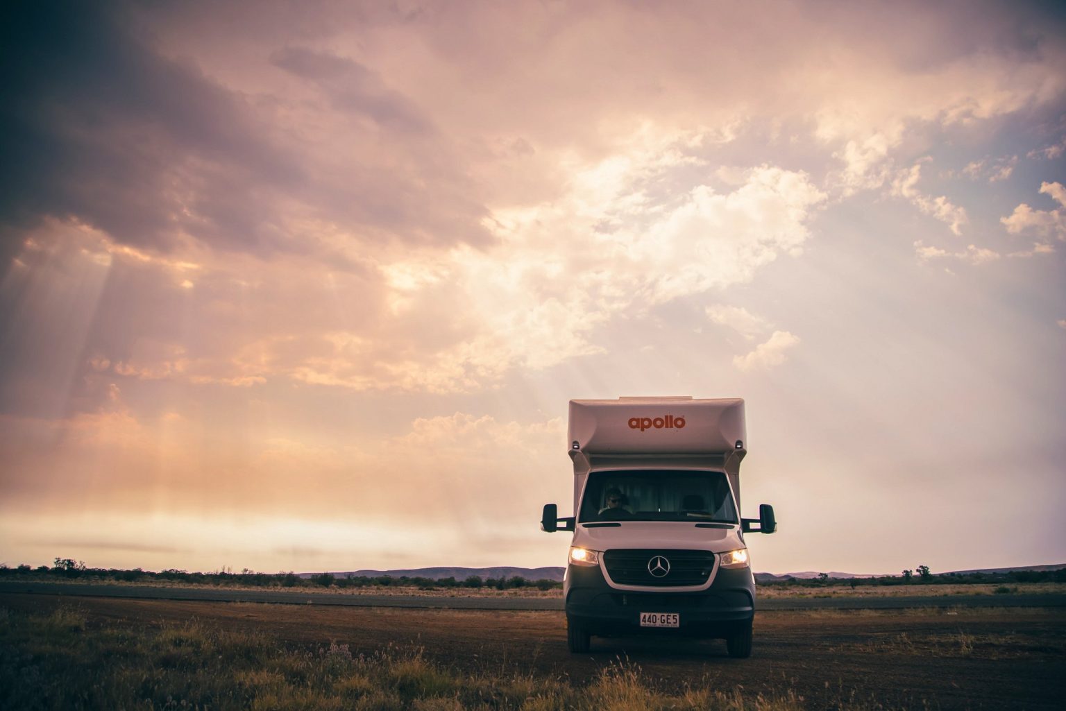 Motorhome in open grassland under dramatic sunset light, Alice Springs, the Northern Territory