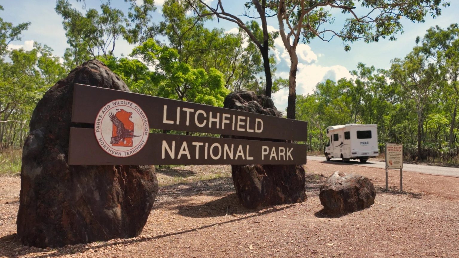 National park entrance sign with a campervan parked behind, the Northern Territory