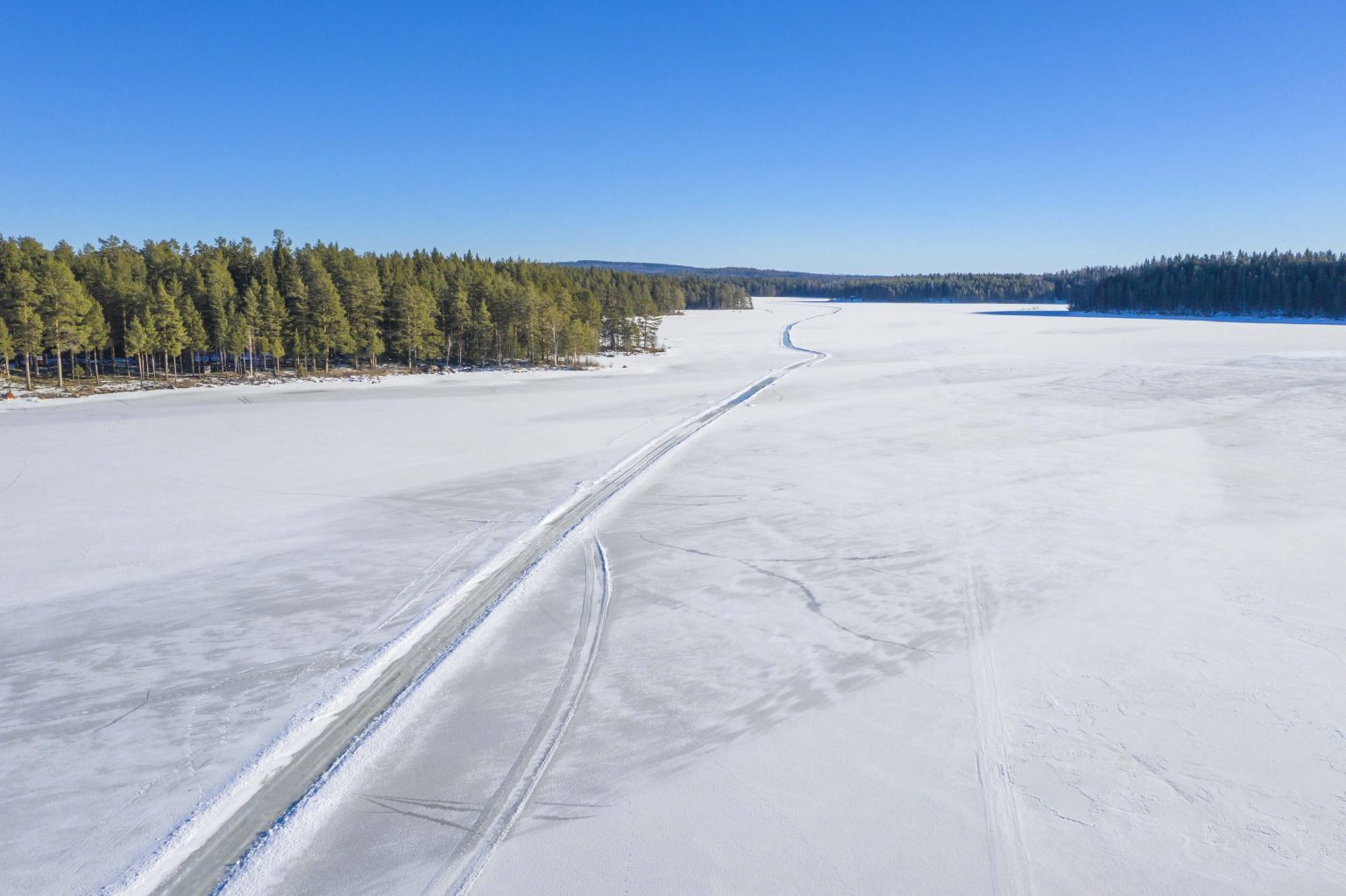 An ice road across a frozen lake through pine forest, Sweden