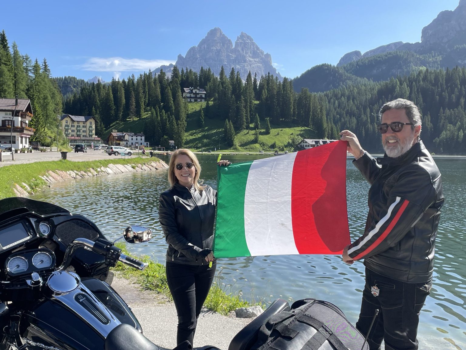 Couple holding an Italian flag by a mountain lake in the Dolomites