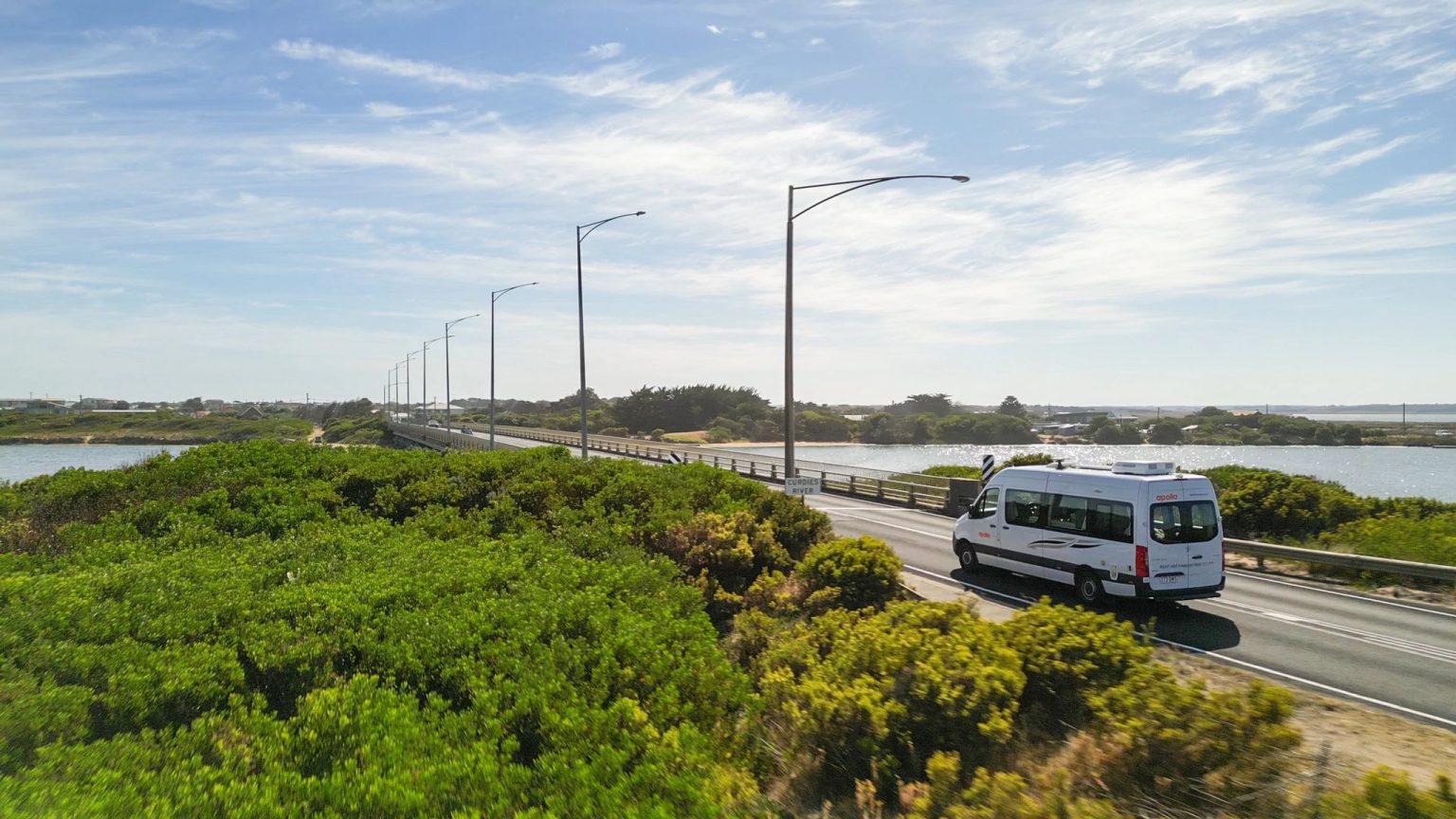 Campervan on a coastal road past green scrub, Great Ocean Road, Victoria