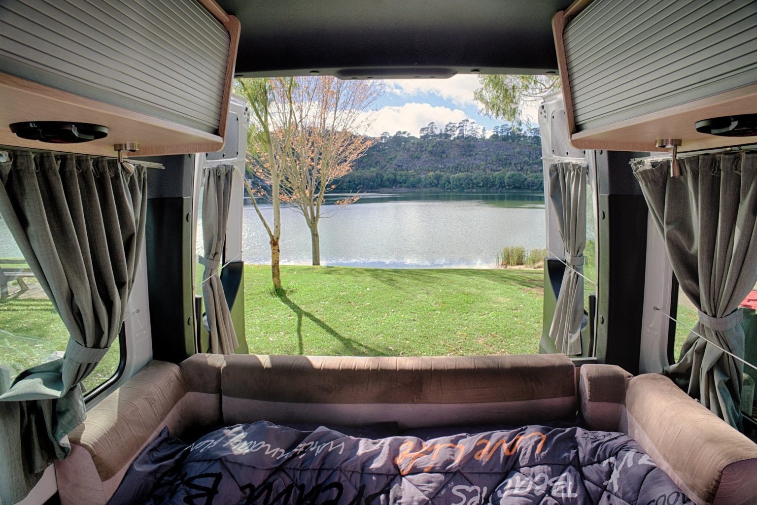 View from the campervan bed through open rear doors to a lake, Valley Lake, Mount Gambier, South Australia