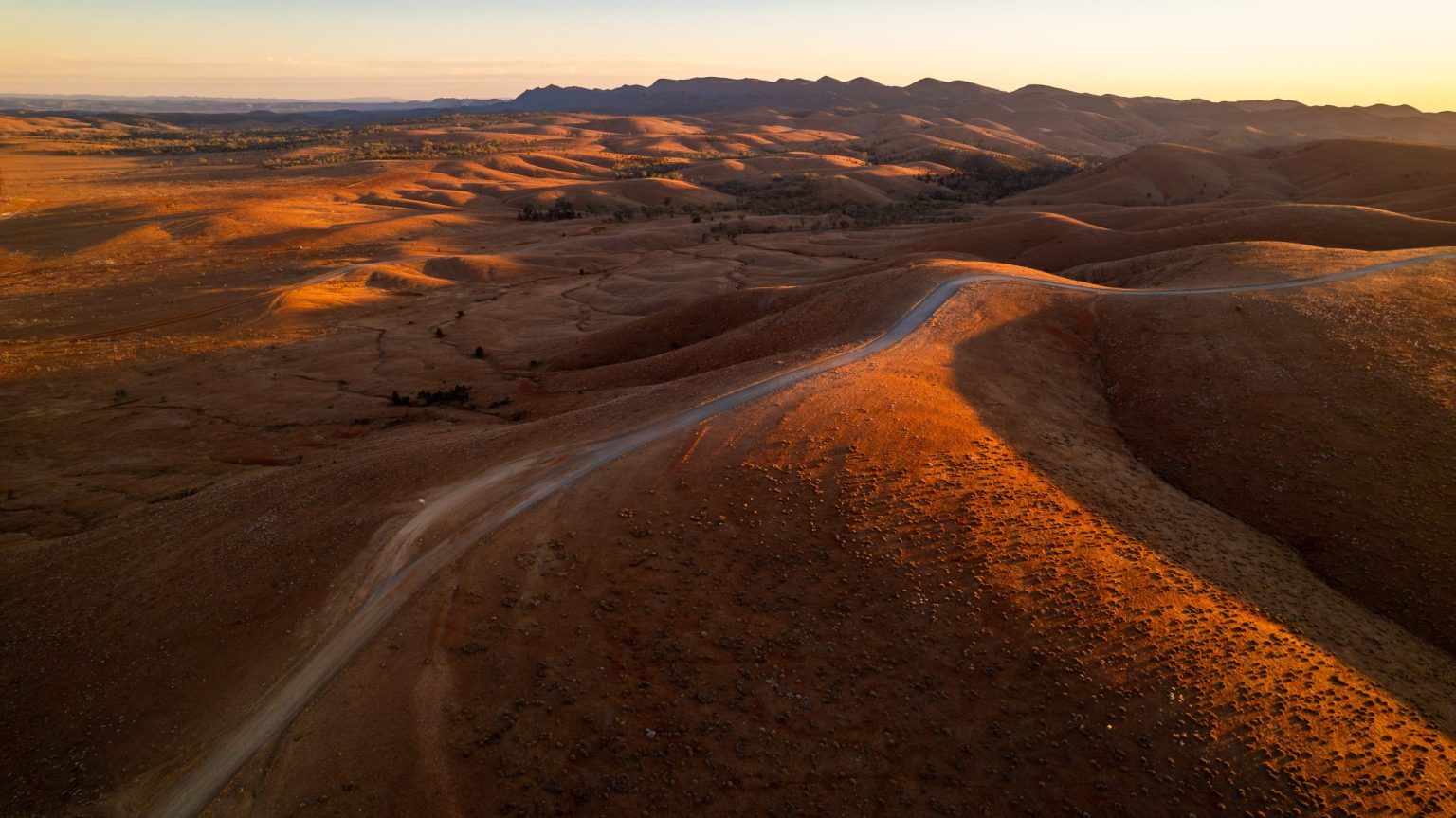 Track across desert dunes at sunset