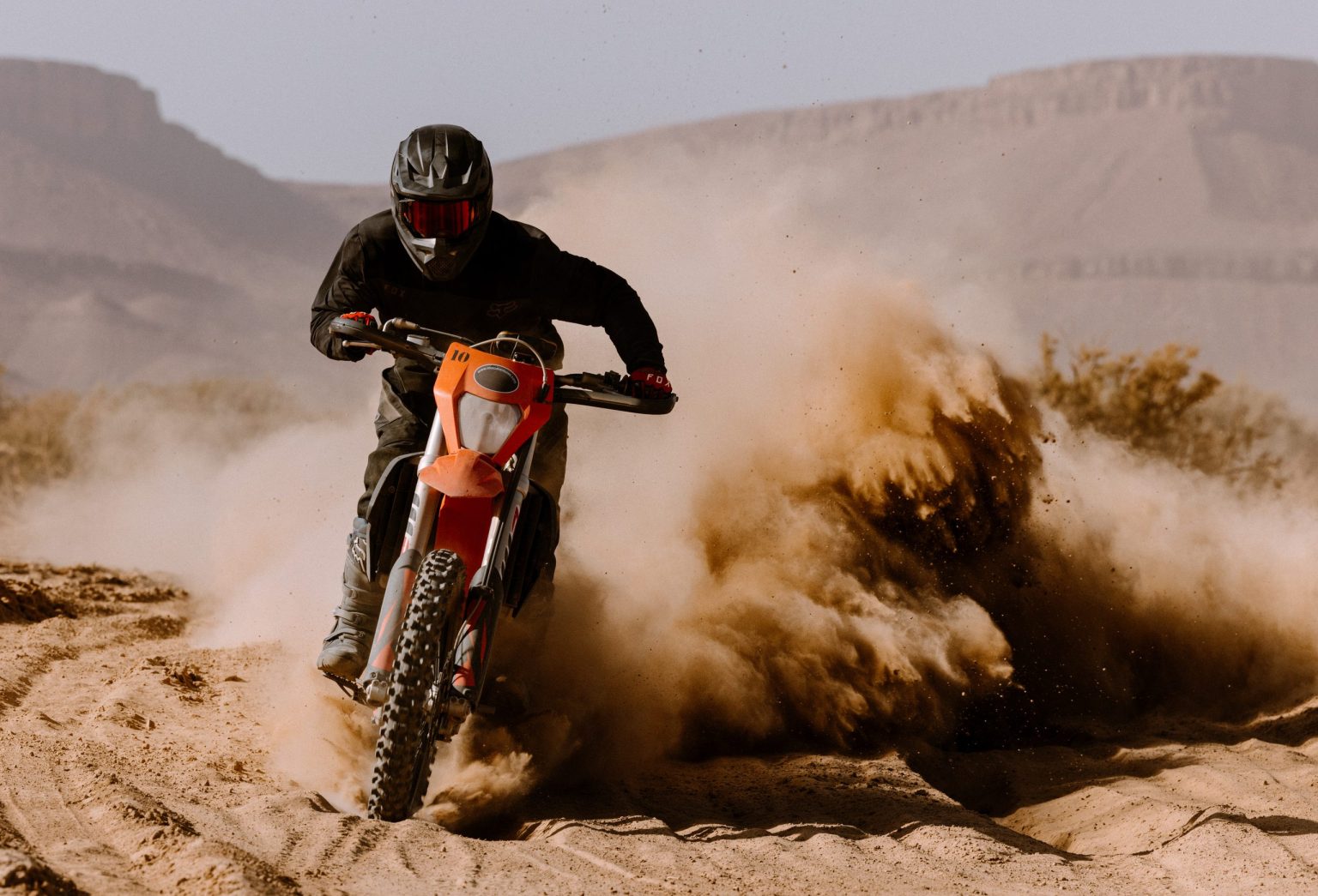 Motorcyclist spraying sand on a desert trail in Morocco