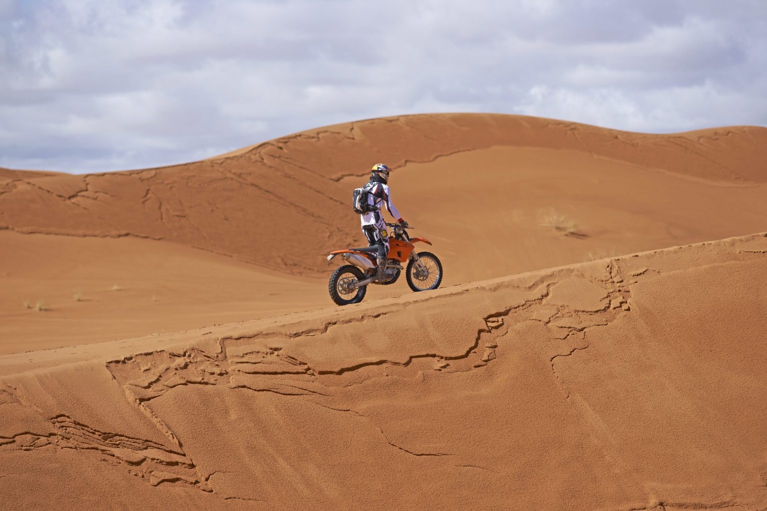 Motorcyclist riding across Sahara sand dunes