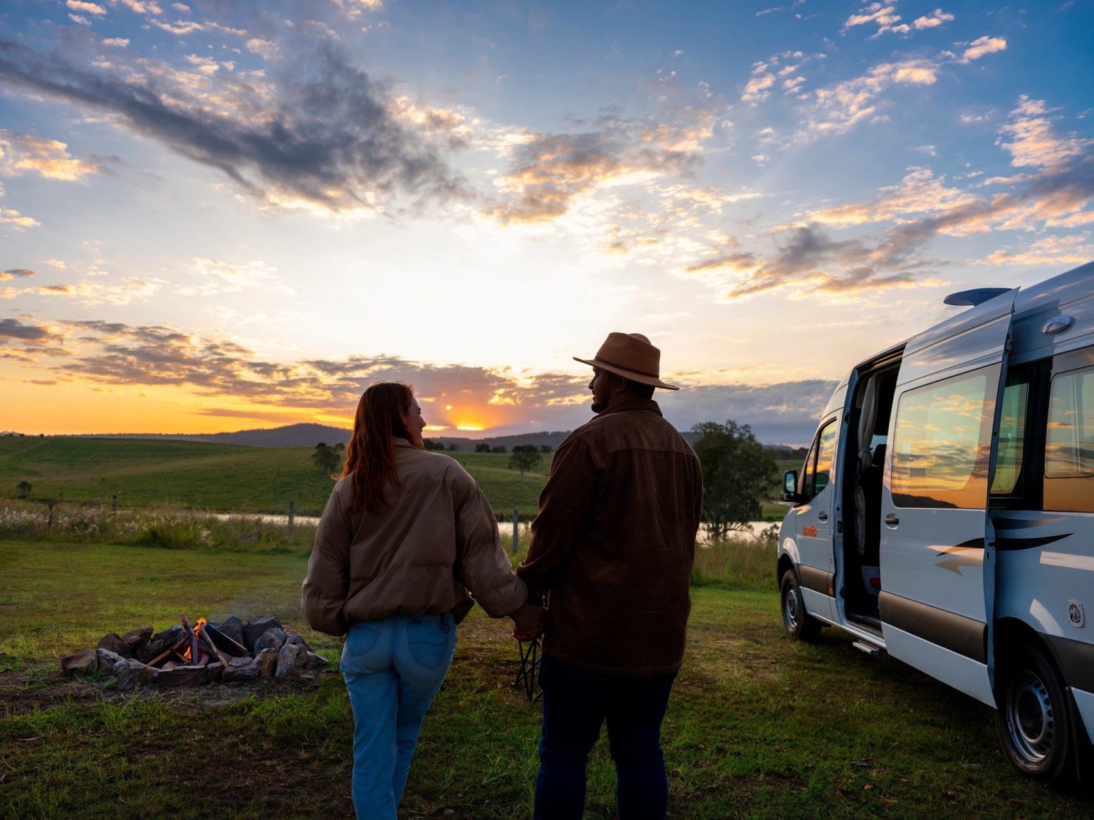 Couple watching the sunset beside a parked campervan, South East Queensland