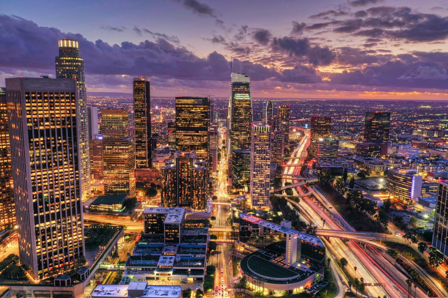 Downtown Los Angeles skyscrapers and freeways lit up at dusk