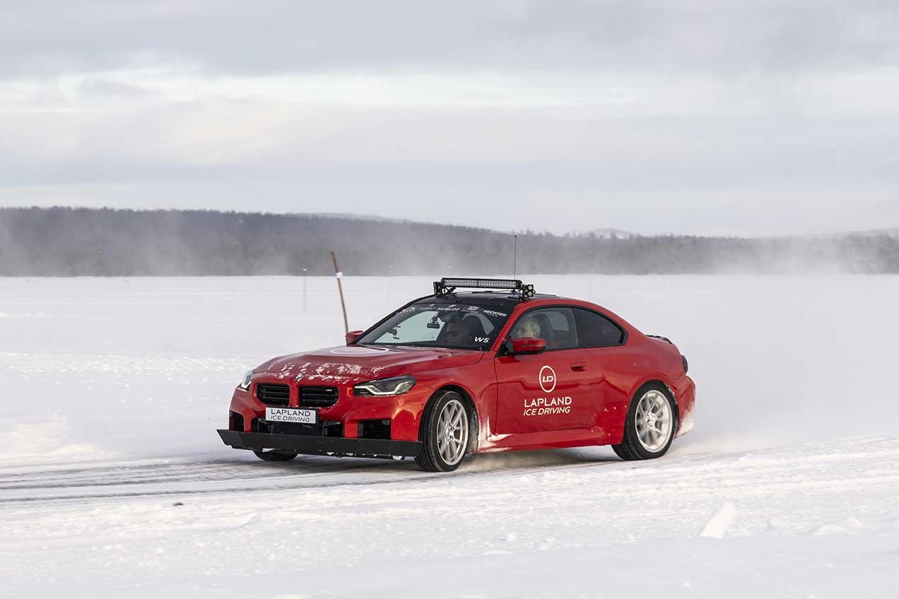 Red BMW coupe with roof light bar driving across a frozen lake