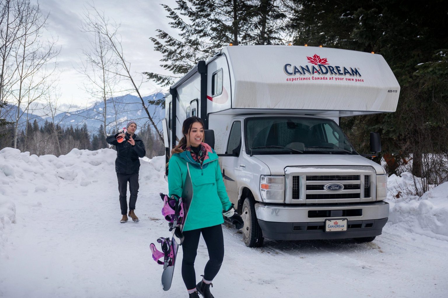 Skiers walking through snow beside a motorhome, Canada