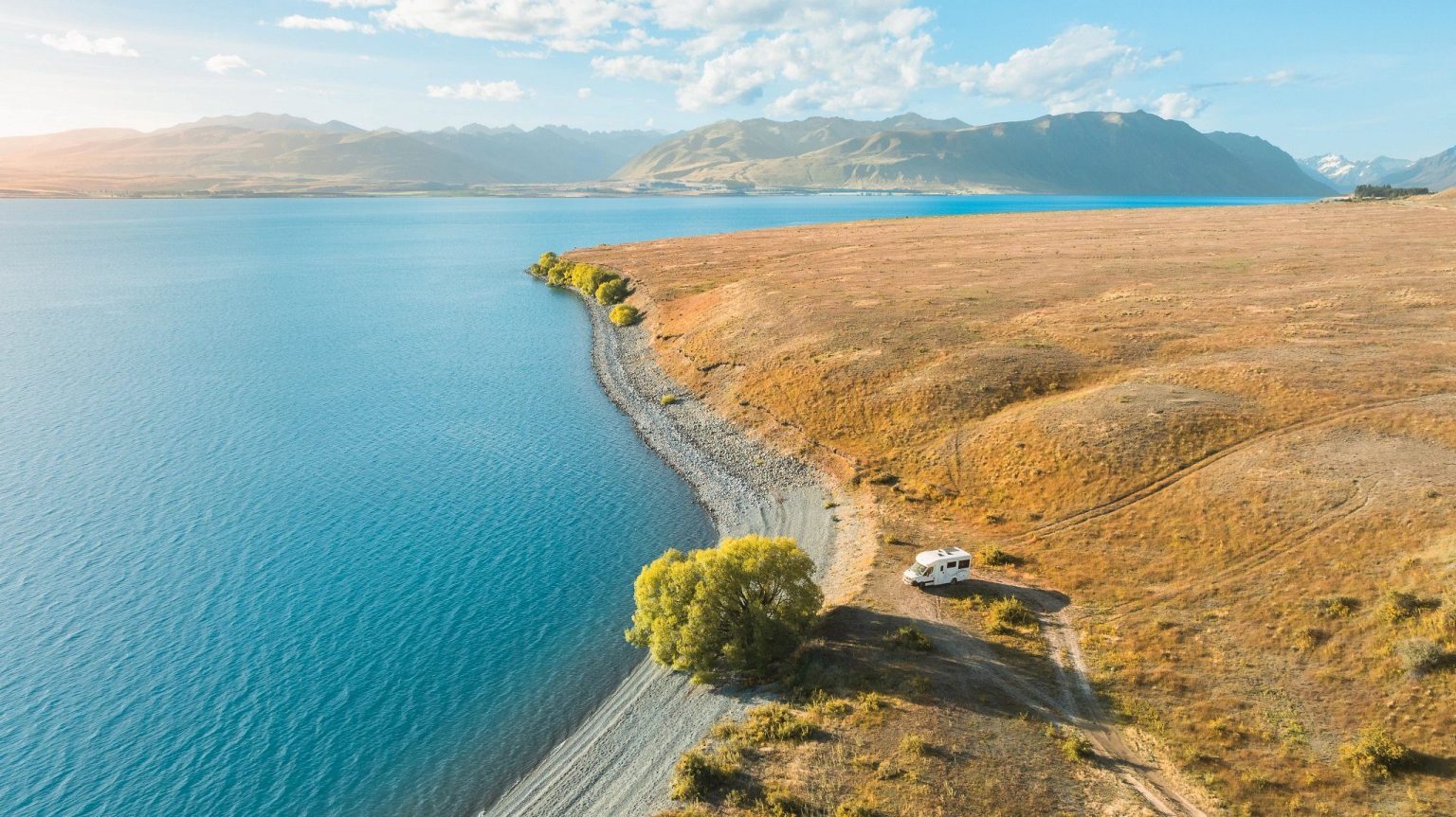 Aerial view of a lakeside road through golden tussock hills, Lake Tekapo, New Zealand's South Island