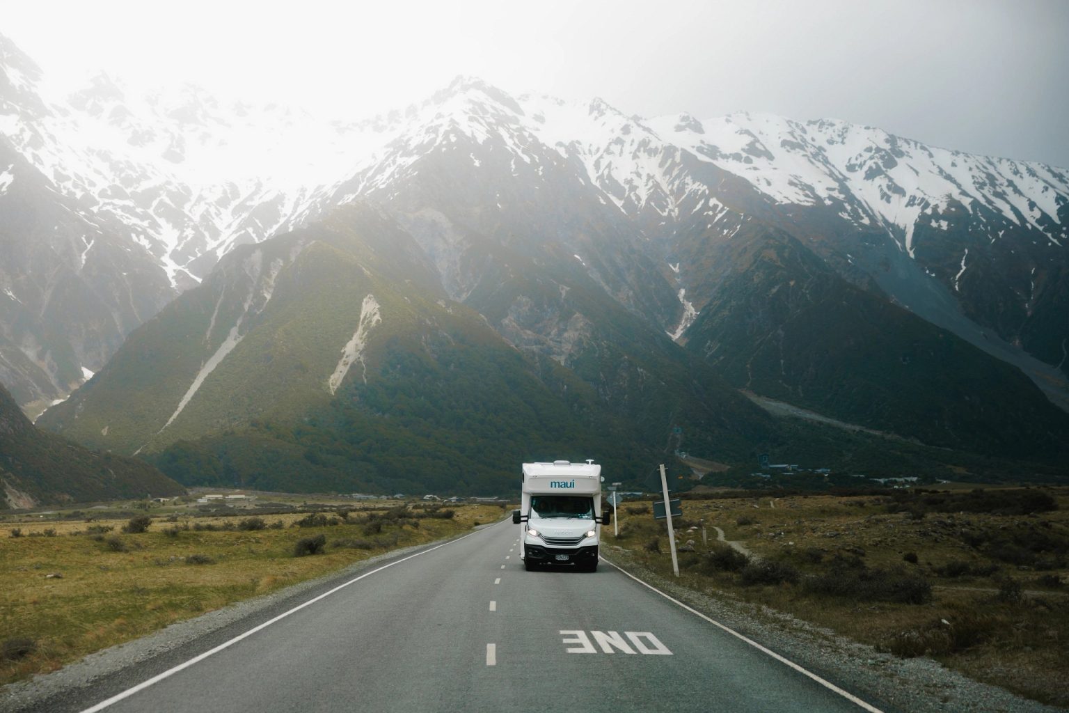 Motorhome driving towards snow-capped mountains on an open road, Aoraki/Mount Cook National Park, New Zealand's South Island