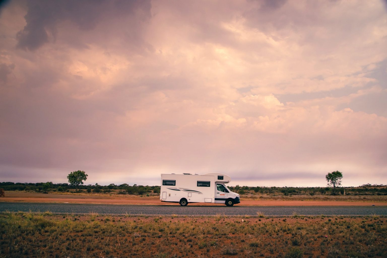 Motorhome on an outback road beneath dramatic pink clouds, Alice Springs, the Northern Territory