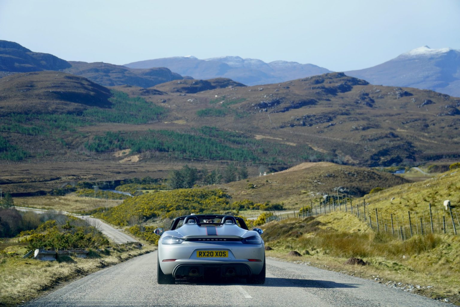 Porsche Boxster on a Highland road below the mountains of Wester Ross