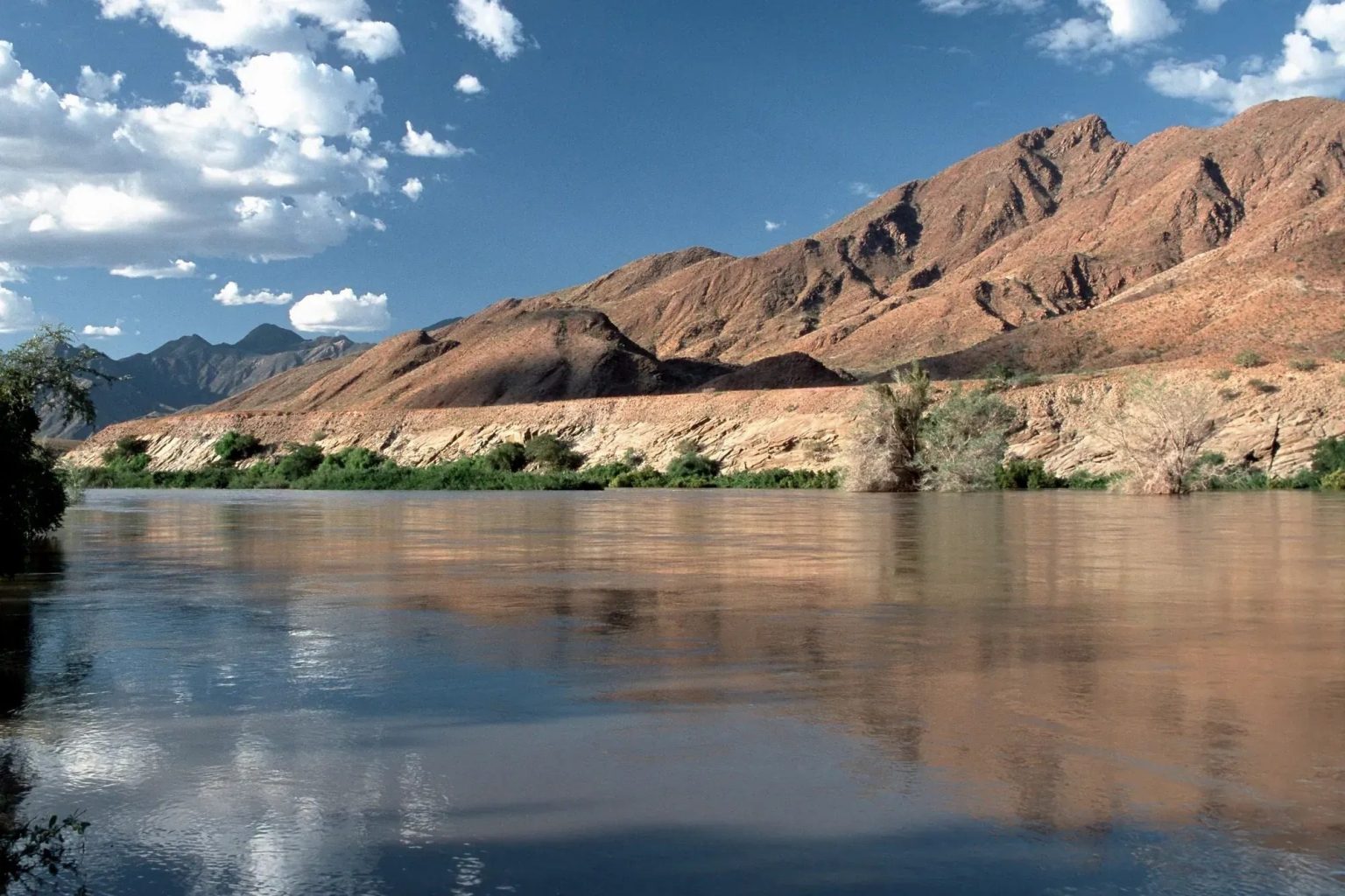 The Kunene river below red mountains in the far north-west of Namibia
