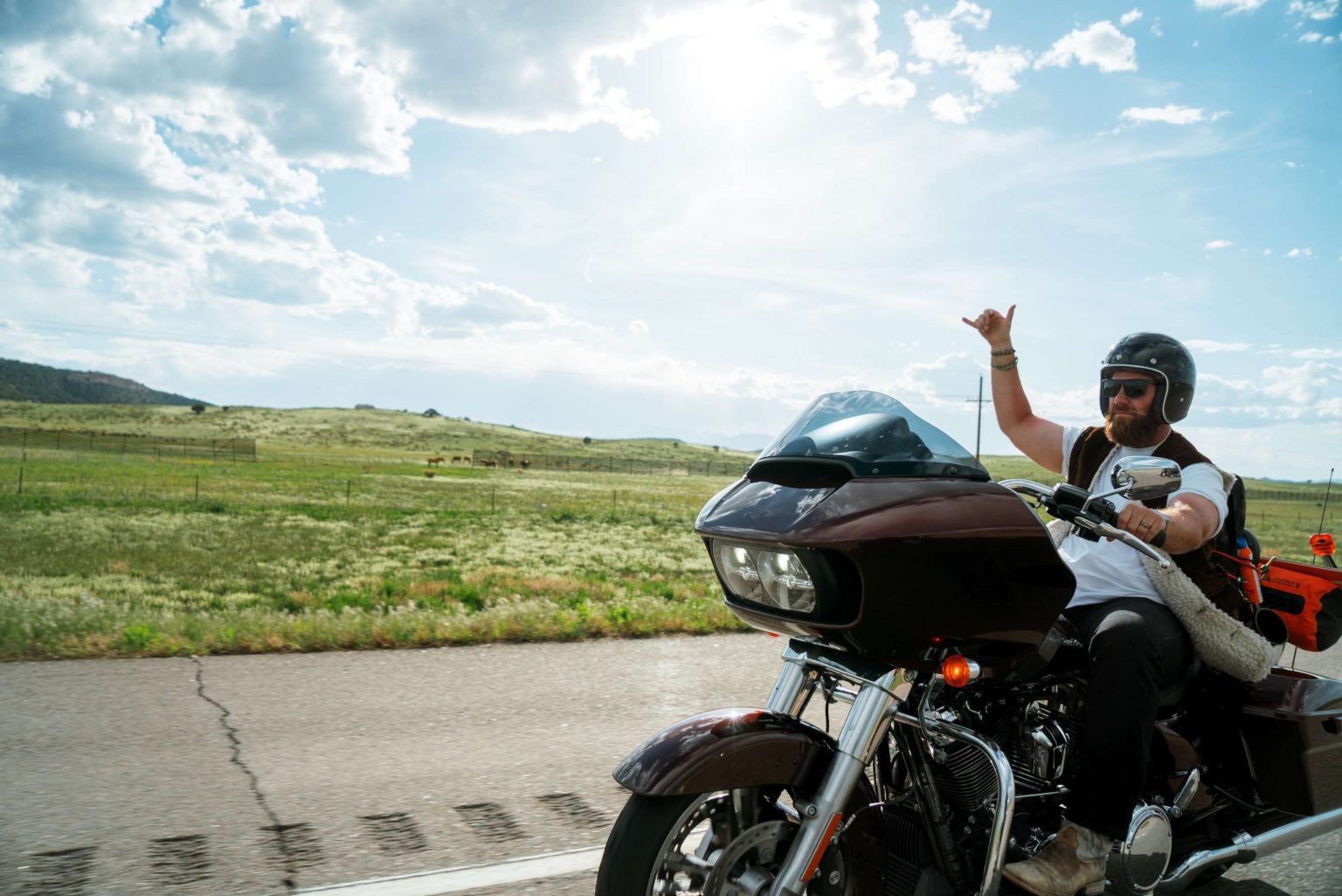 Rider waving from a Harley-Davidson Road Glide on the open prairie