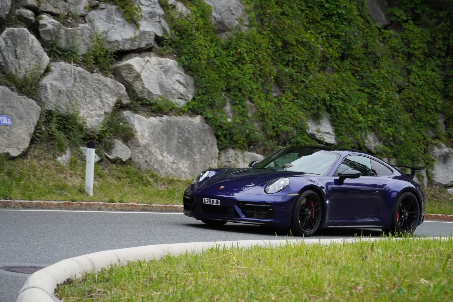 Purple Porsche 911 on a hairpin bend in the Swiss Alps