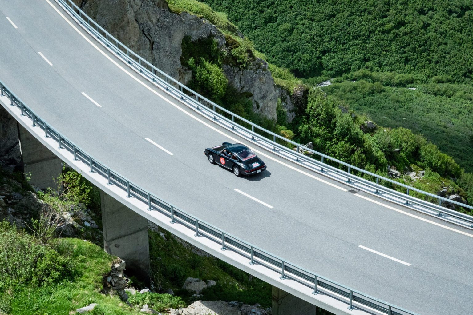 Porsche on a curving mountain viaduct in the Swiss Alps