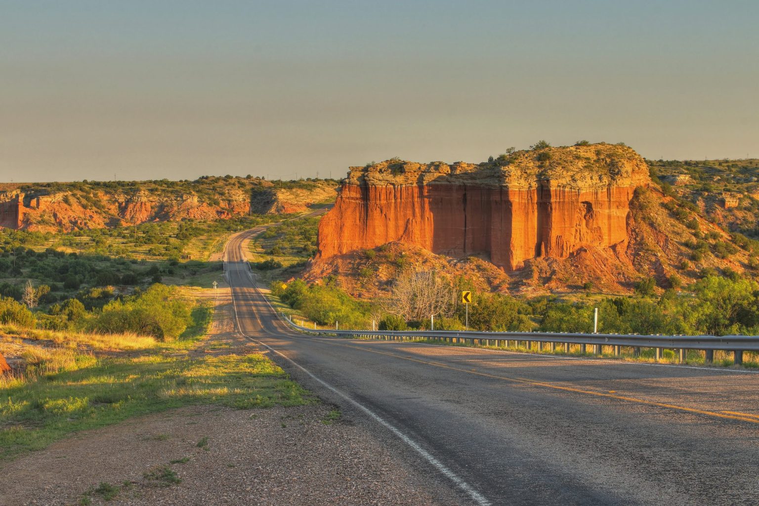 Empty road leading to red rock cliffs in Palo Duro Canyon, Texas