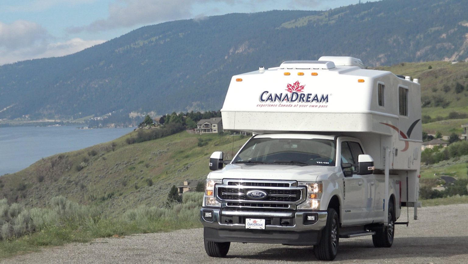 Truck camper on a hillside road above a lake, Okanagan, Canada