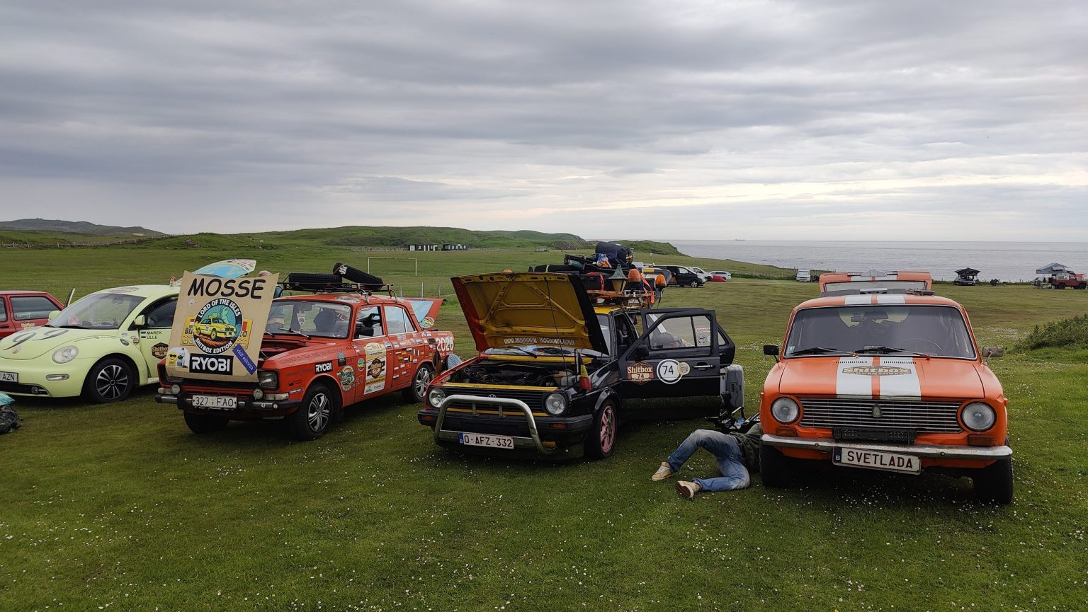 Rally cars parked on a clifftop meadow above the sea