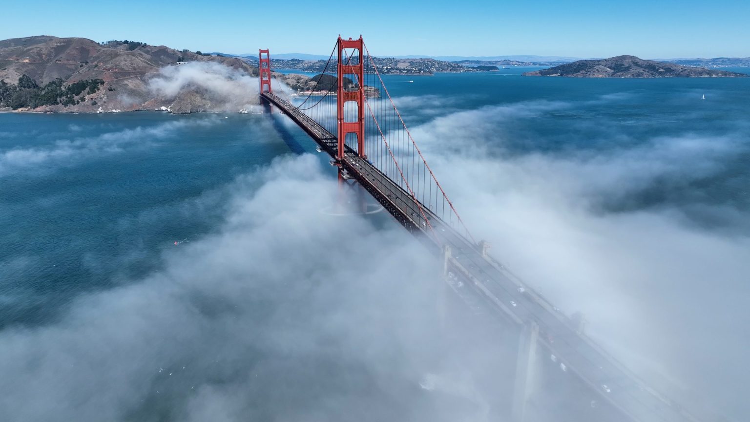 Aerial view of the Golden Gate Bridge rising through fog over San Francisco Bay