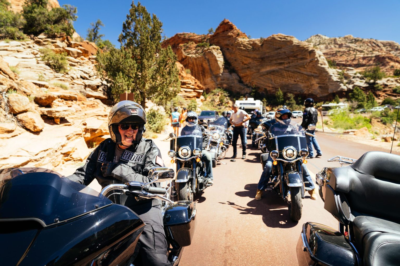 Group of riders on Harley-Davidson touring motorcycles stopped among red rock in Utah canyon country