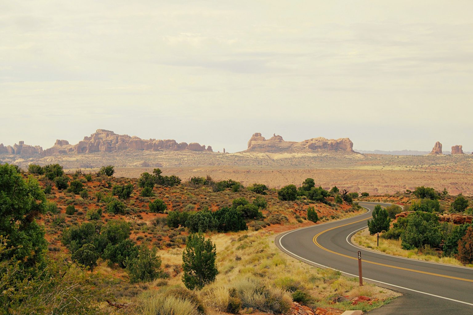 Winding road through desert scrub toward red rock formations in Utah